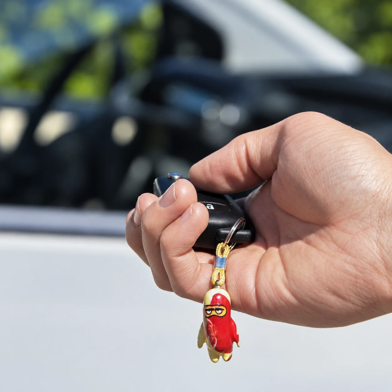 Red charm hanging from a car key in a hand
