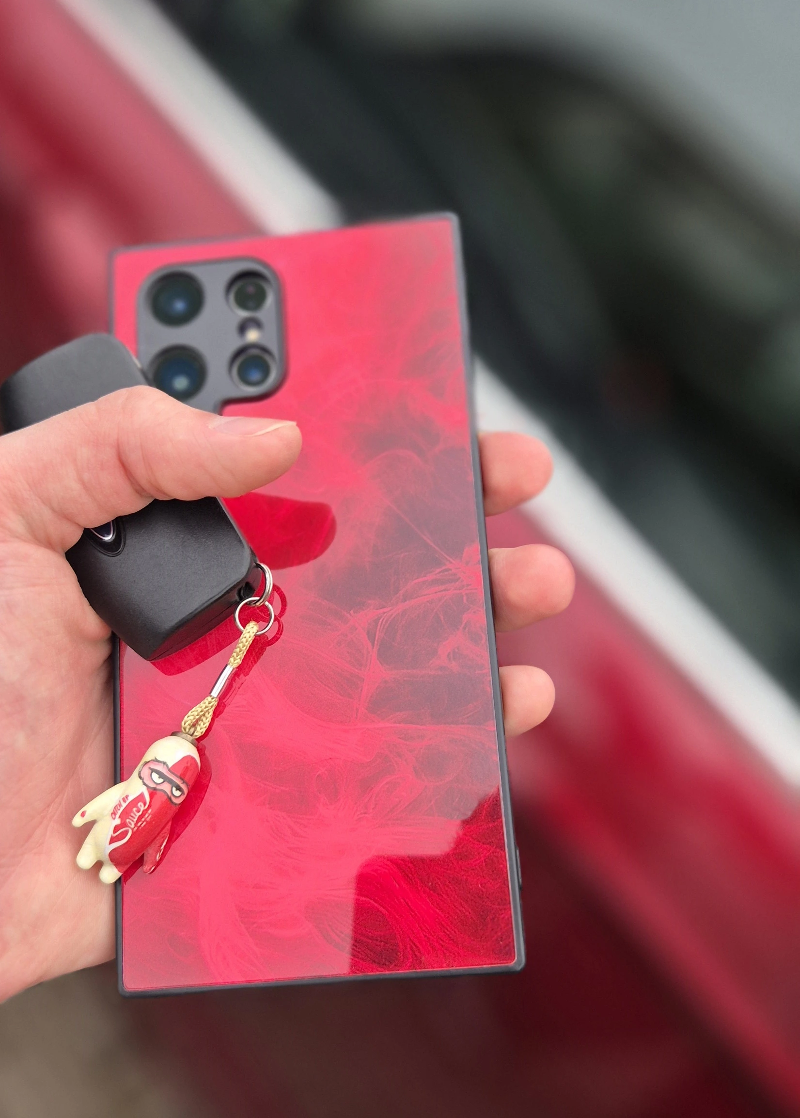Red charm hanging from a phone and car key